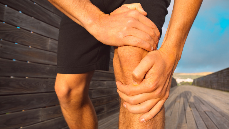 Man runner holding his painful knee because of injury. 