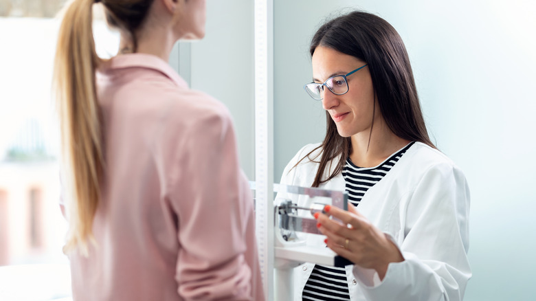 doctor taking patient's height and weight