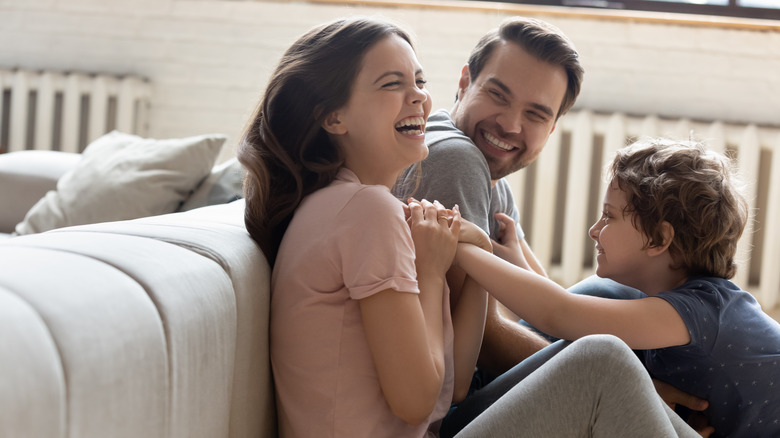 Son is tickling mother while father laughs nearby