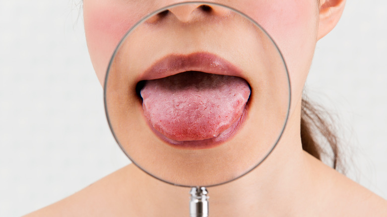 Woman sticks out their tongue under a magnifying glass