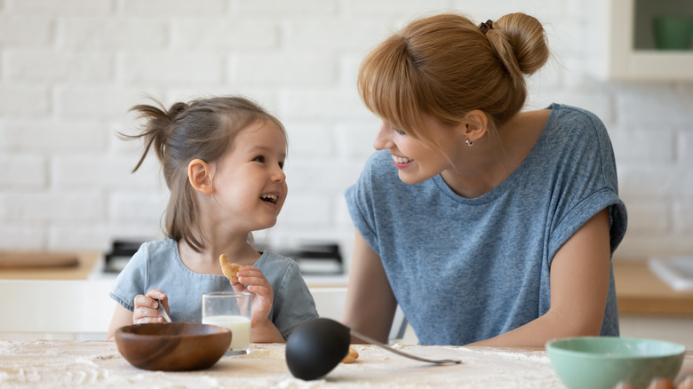 A mother is sitting by her child as the child eats