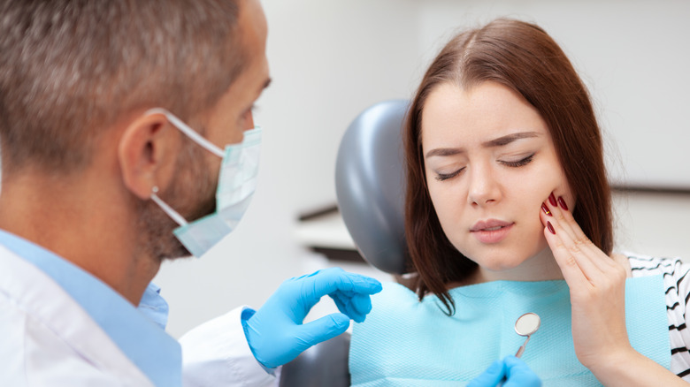Woman at dentist holding mouth in pain
