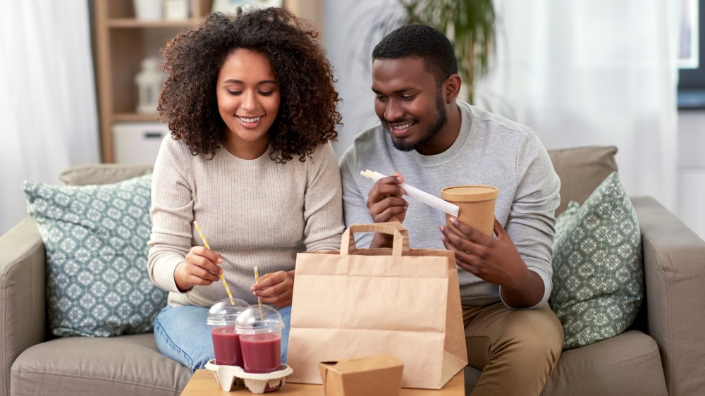 a couple on the couch opening take-out food 