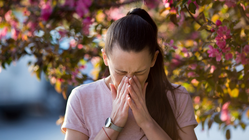 Woman standing outside and sneezing
