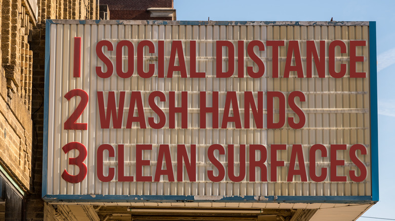 A sign listing 'social distance', 'wash hands', and 'clean surfaces'