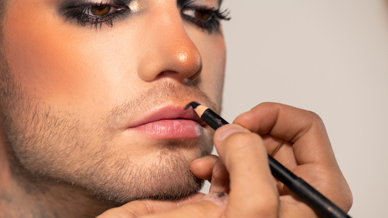 man applying lip liner