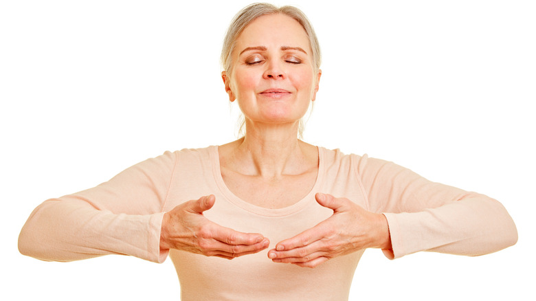 Woman eyes closed raising hands up toward chest