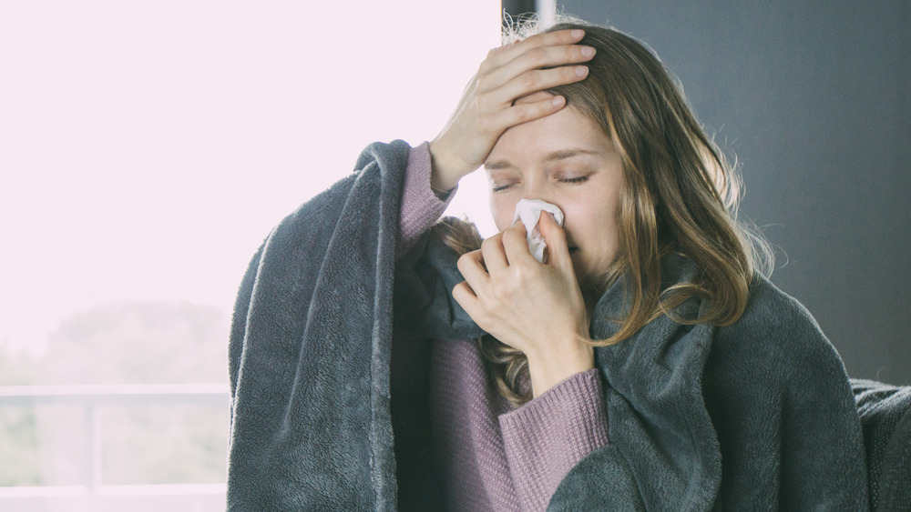 Woman with stuffy nose wrapped in blanket