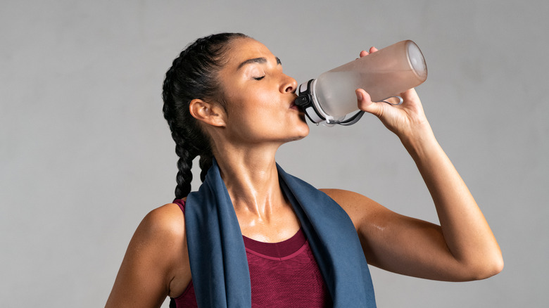 ﻿﻿Woman drinking water with gray background