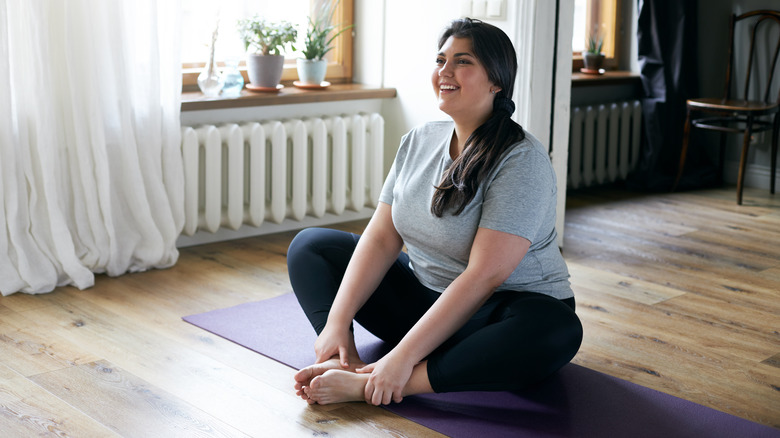 Woman in activewear sitting on mat 