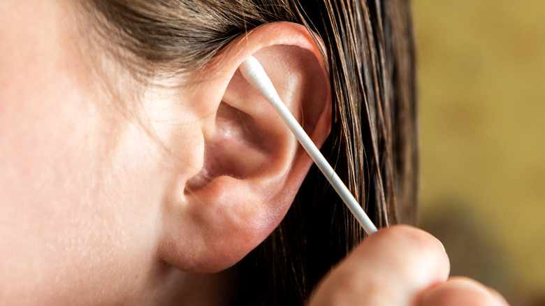 Woman cleaning outer part of ear with Q-tip