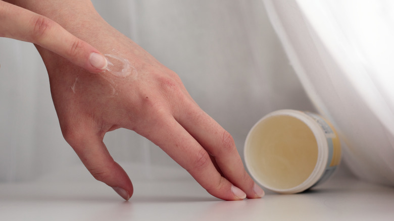 Woman applying petroleum jelly to hand