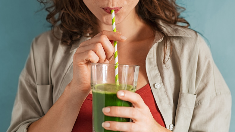 A woman drinks green juice