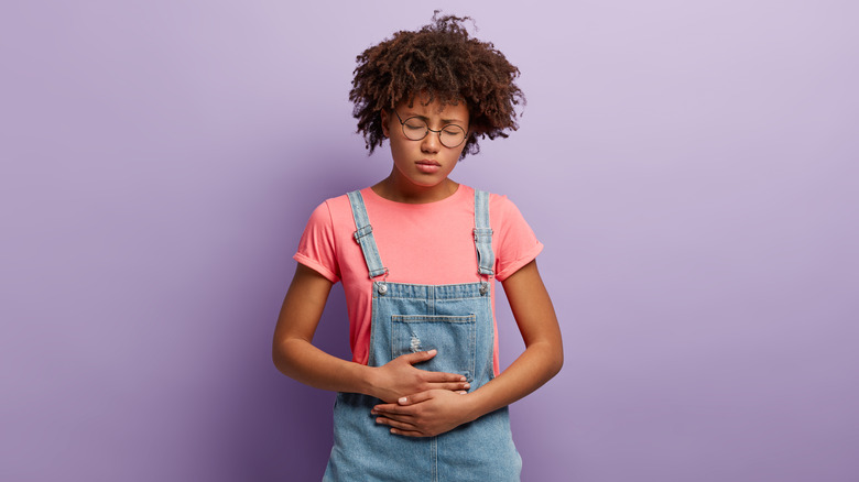 Girl with hands clutching upset stomach