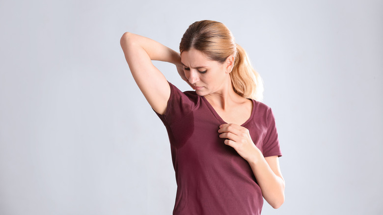 Woman looking at sweat stain near armpit