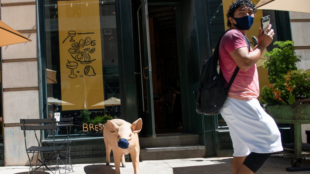 Man and pig statue wearing masks over mouth and nose