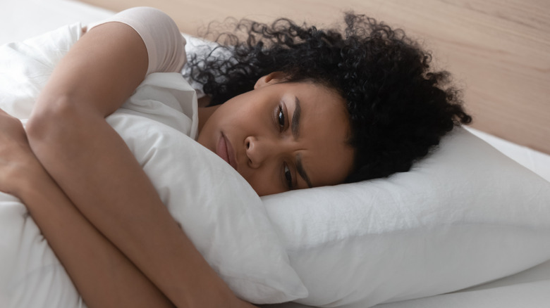 woman lying in bed looking sad