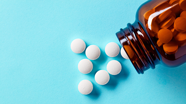 White pills and tablets spilling out of a drug bottle