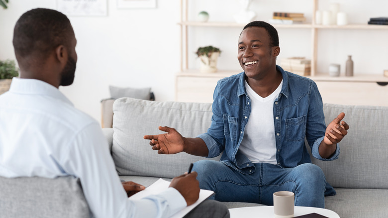 Cheerful black man talking to psychologist during meeting at his office