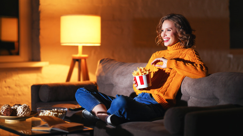 Woman eating fries while watching TV