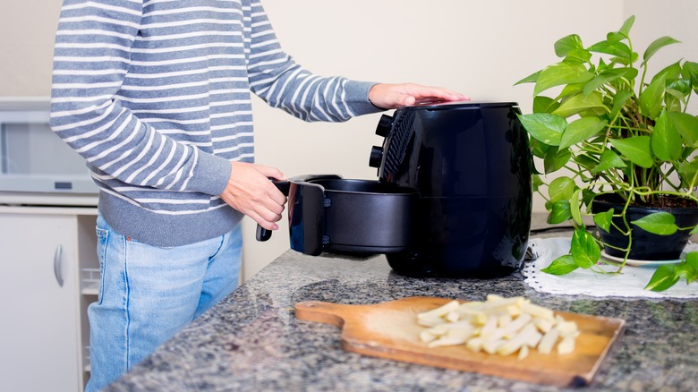 Man cooking French fries in an air fryer