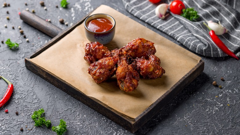 Chicken wings with ketchup on a wooden board