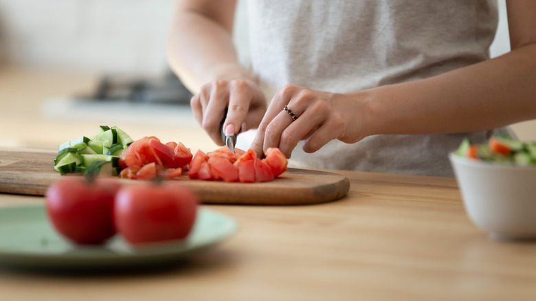 Someone cuts up tomatoes in their kitchen