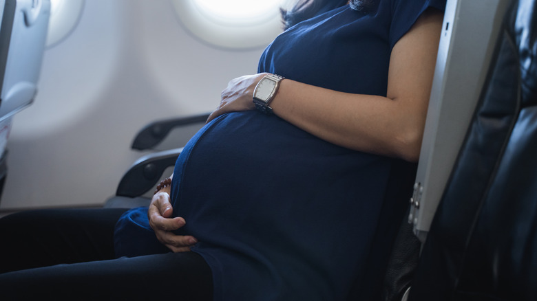 pregnant woman sitting in an airplane seat 