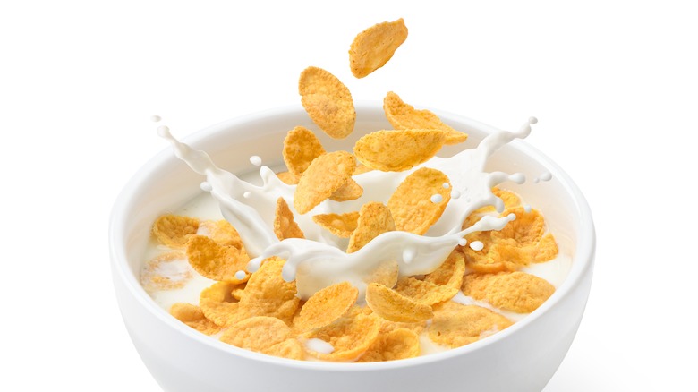 Bowl of cornflakes with a splash of milk against a white background