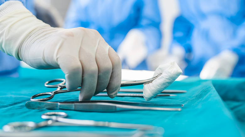 A doctor reaching for their surgical tools