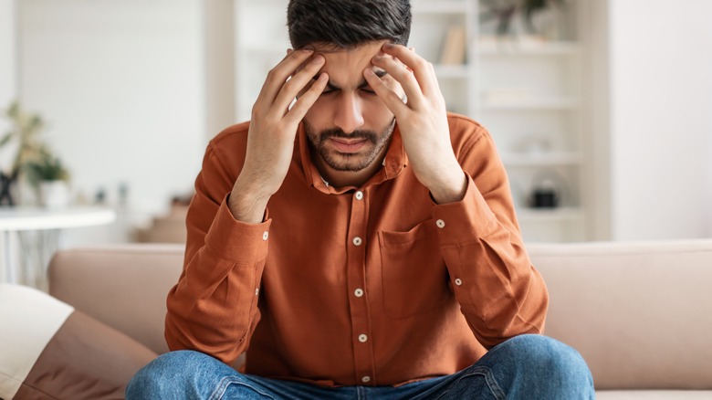 man digging fingers into temples due to migraine