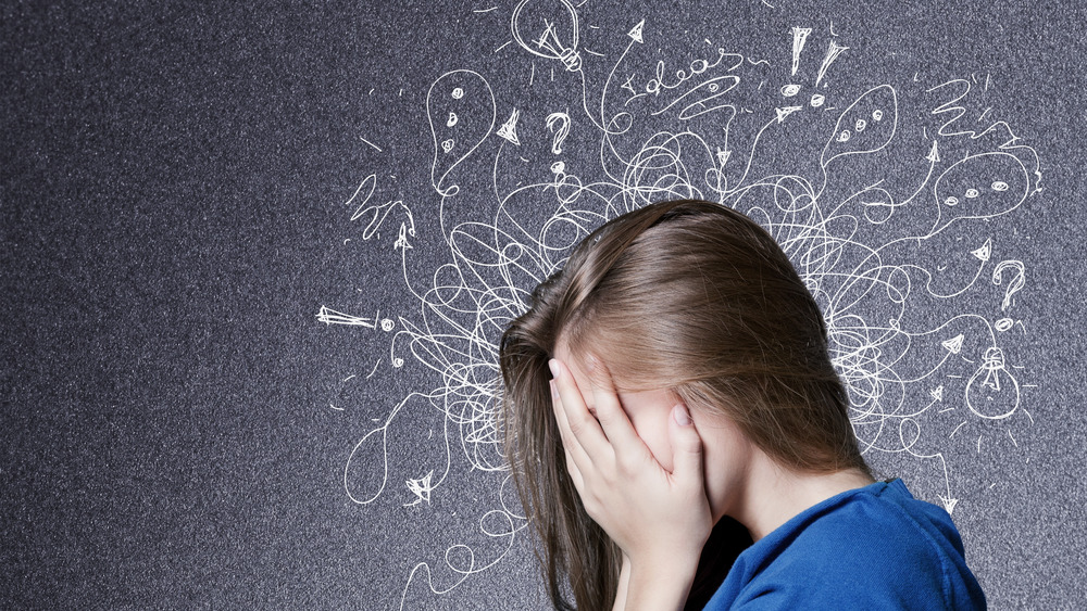 Woman with hands covering face surrounded by lines and question marks