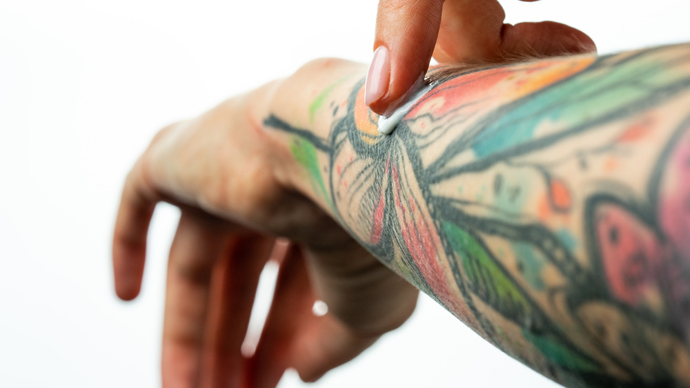 Close up of woman applying cream to tattoo