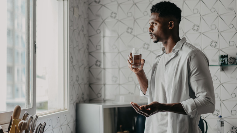 Man holding medication and glass of water