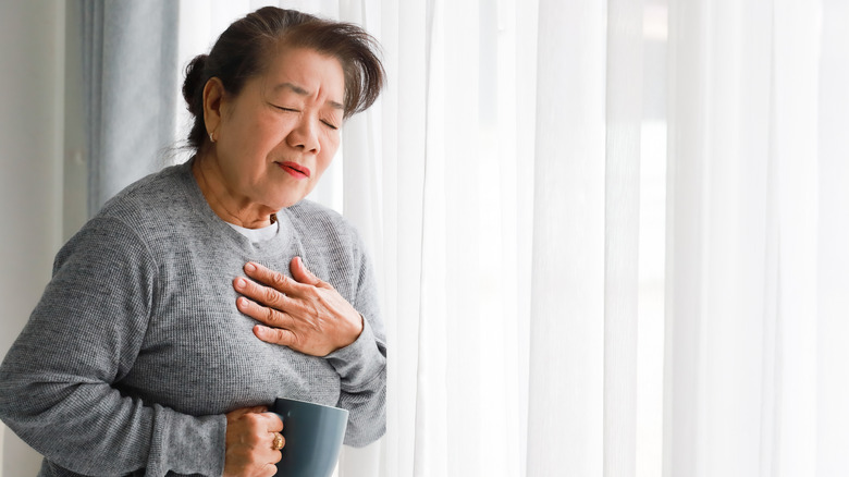Woman holding hand to chest in pain
