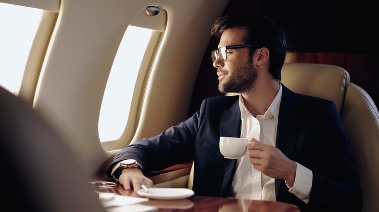 Man drinking a cup of coffee on a plane