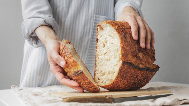 woman handling a cut loaf of sourdough bread