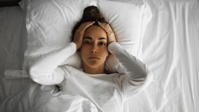 woman awake in bed holding her head