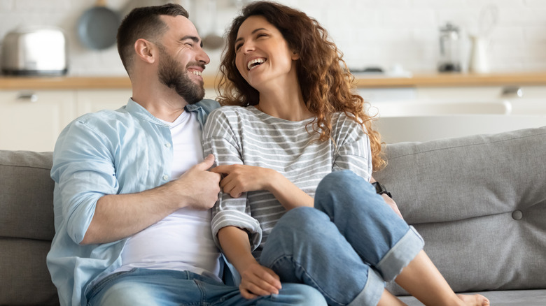 embracing woman and man smiling on couch