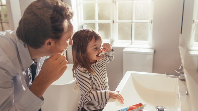 Father and daughter brushing teeth