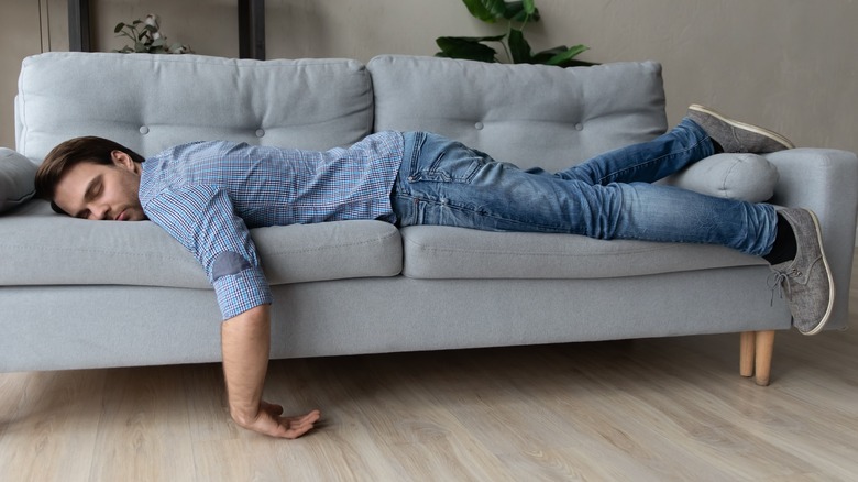 Man lying on couch exhausted