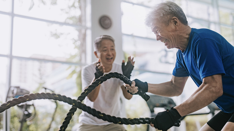 senior man slamming battle ropes at the gym