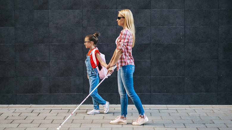 young blind mother walking with daughter