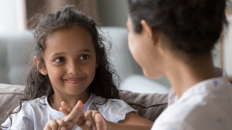 Young girl smiling and practicing sign language