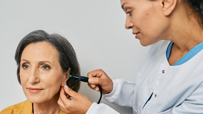 Doctor examining woman's ear