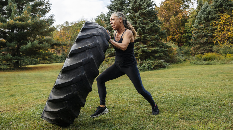 A strong middle-aged woman flipping a truck tire