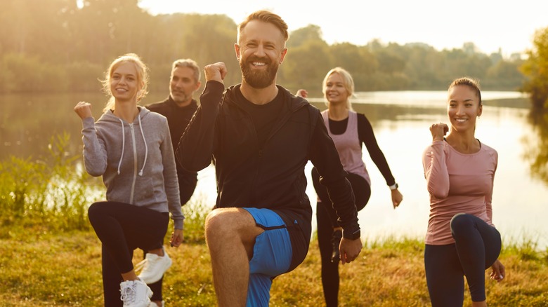 A group of men and women doing high knees by a lake