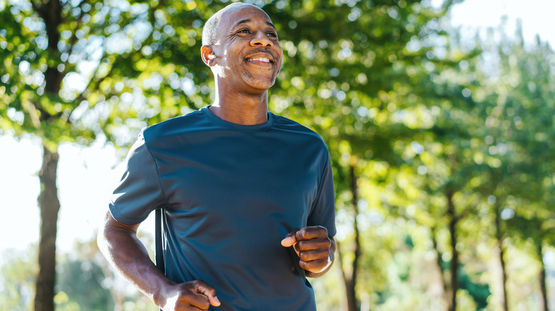 A smiling older man running in the park