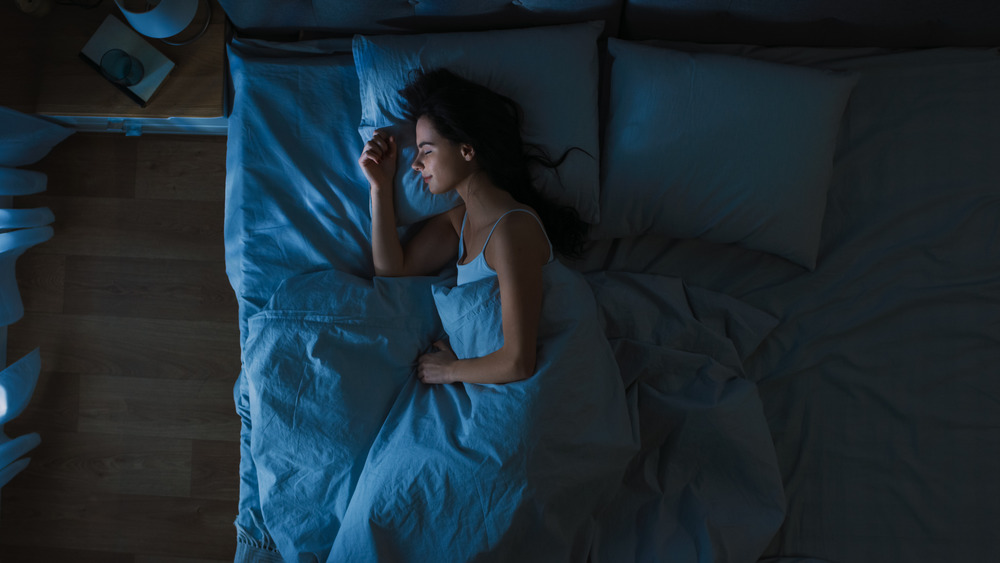 woman smiling while sleeping in bed in dark room