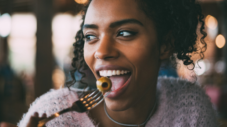 woman eating olive on fork